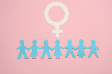 Feminism. Female gender symbol and paper cut human chain on pink background