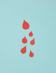 Paper-cut blood drops on a blue background. Donation
