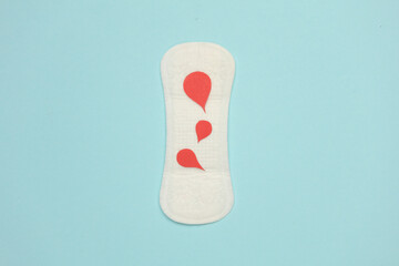 Pad with blood drops on blue background. Women's monthly period