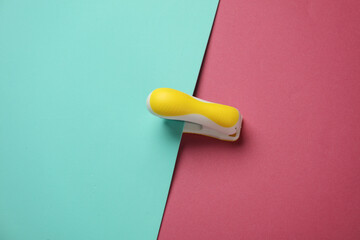 Yellow Stapler on pink blue background. Top view