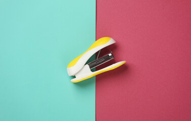 Yellow Stapler on pink blue background. Top view