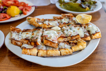 Turkish pita with minced meat and cheddar cheese on a white plate.