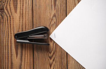 Stapler with a sheet of paper on a wooden table