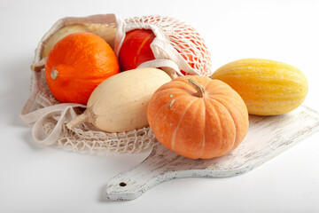 Seasonal colorful pumpkins in string bag on white background