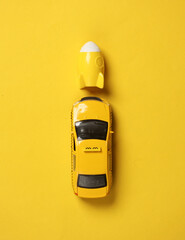 Toy taxi car model with space shuttle on yellow background. Startup, business concept. Top view