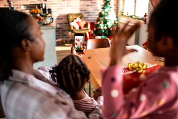 Young mother showing her children santa on the smartphone at home