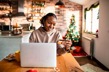 Young woman online shopping from a laptop at home during the Christmas holidays