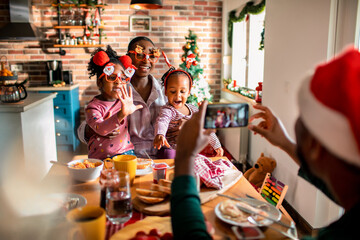 An African American mother and her daughters pose playfully for a Christmas photo