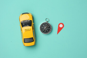 Taxi Car model with geolocation point sign and compass on blue background. Navigation. Flat lay