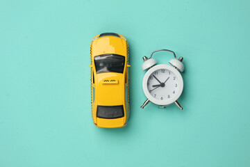 Taxi car with alarm clock on a blue background. Top view