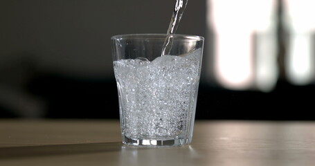 Pouring sprinkling water into glass cup . Serving hydrating drink