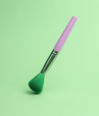 makeup brush flying in antigravity on green background with shadow. Levitation object in the air. Beauty and fashion concept. Creative minimalist layout