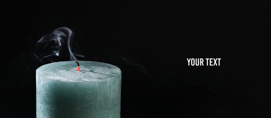 Smoking, extinguished wax candle on a black background. Copy space