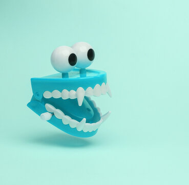 Fanged jumping jaw with eyes flying in antigravity on blue background with shadow. Levitation object in the air. Halloween minimal layout