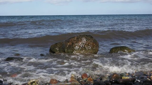 Brandung, Wellen peitschen gegen Steine am Strand der Ostsee