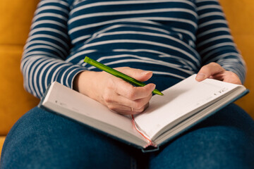 woman in jeans and a striped sweater makes notes in a notepad 