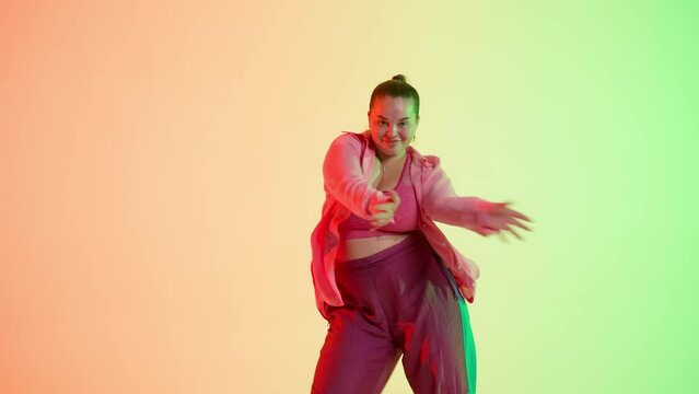 Attractive woman dancing jazz-funk on red and green neon background in a studio. Modern dynamic and energetic dance choreography. Medium full.