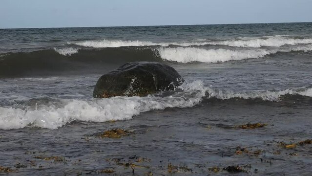 Brandung, Wellen peitschen gegen Steine am Strand der Ostsee