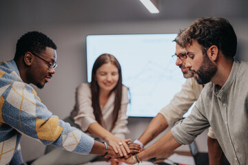 Multicultural business team brainstorming in a conference room, discussing blueprints, graphs, and info graphics. Executives and engineers successfully collaborate on a project.