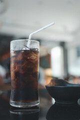 A glass of soft drink and ice with white straw at restaurant