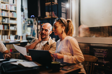 Business partners meet in a coffee bar, discussing project details, budget, and profitability. Their confident teamwork and remote work abilities ensure success.