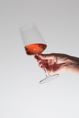 A hand holding a glass with rose wine