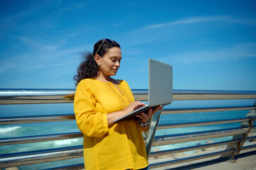 Purposeful female developer, trader, manager online working on laptop outdoor