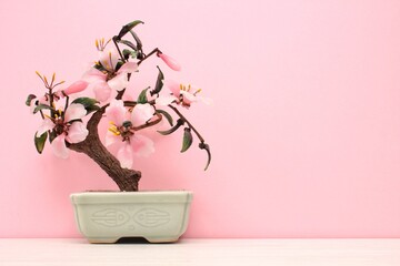 Artificial sakura bonsai tree on ceramic pot with pink background. Glass cherry blossom for home decor. Spring flower branch in scandi style interior. Hygge design. Zen, relax concept. Copy space - Powered by Adobe
