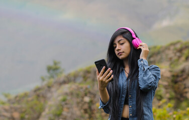 Mujer joven atractiva con auriculares disfrutando de música o un podcast en el parque o bosque,...
