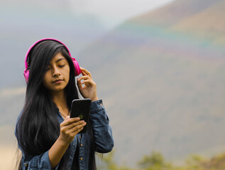 Mujer joven atractiva con auriculares disfrutando de música o un podcast en el parque o bosque,...