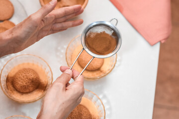 Sprinkling cinnamon on top of the custard as seen from above