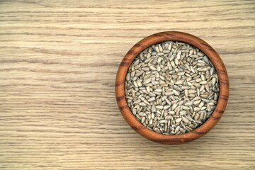 Peeled sunflower seeds in wooden bowl, top view.