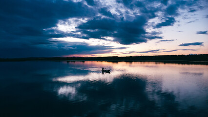 Fototapeta premium sunset over the lake. sunset over the lake. fishing in a boat in the middle of the lake. fishing in a boat at sunset
