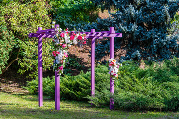 Front view of a decorative pink pergola with artificial flowers in urban garden, closeup
