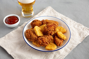 Homemade Chicken Nuggets and Chicken Wings with Ketchup and Beer, side view.