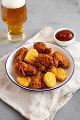 Homemade Chicken Nuggets and Chicken Wings with Ketchup and Beer, side view.