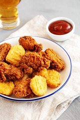 Homemade Chicken Nuggets and Chicken Wings with Ketchup and Beer, side view.
