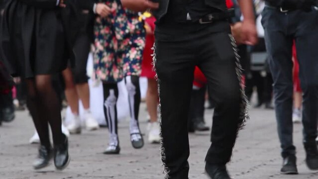 Group of mexican teenagers dancing, wearing traditional mexican folk costumes, mariachi and colorful mexican dresses on the day of the dead