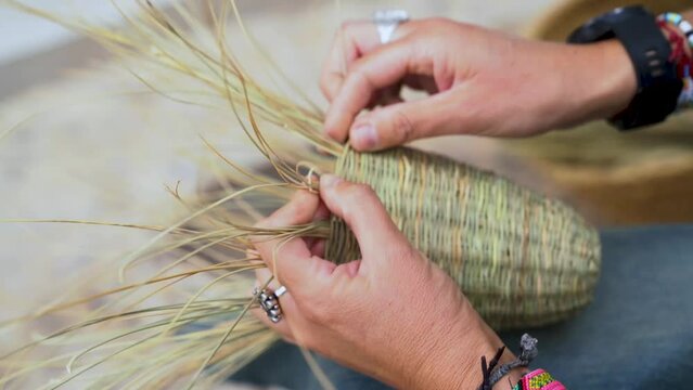 Side view of Hispanic woman weaving a basket with esparto fibers. Manual work, tradition and culture. Close up.