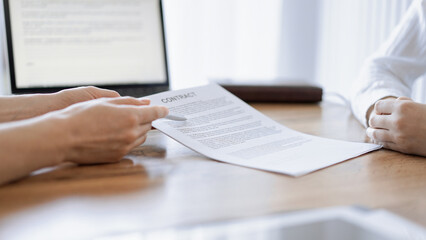 Businesswoman lawyer pointing into contract special points admitting something for colleague or client at the wooden desk in office. Business people teamwork and partnership, meeting concept