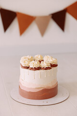 White and pink cake with cream roses on a white background. A delicious and elegant dessert for a birthday, wedding or anniversary. Concept for advertising your bakery or catering business.