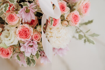 Bouquet of pink and white roses with a ribbon on a beige background. Concept for expressing love, gratitude, wedding or congratulation. Copy space for greeting card or invitation.