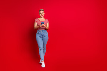 Full length photo of lovely positive girl in trendy clothes hold iphone samsung demonstrate empty...
