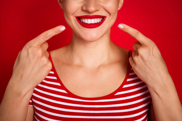 Close up cropped photo of cheerful caucasian young woman point fingers ideal perfect hollywood smile isolated on red color background