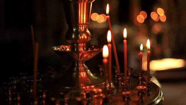 burning candles in a temple or church in the dark standing in a candlestick