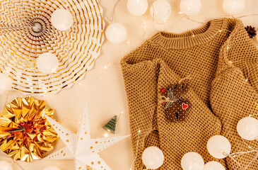 knitted sweaters, led lights on beige background. Hygge style, winter concept. Cozy home desk.  New...