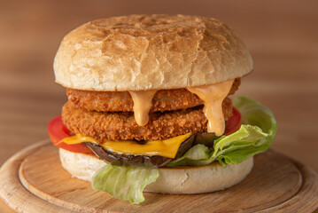 smoked chickenburger with aubergine, salad, tomato, and sauce centred on wooden plate