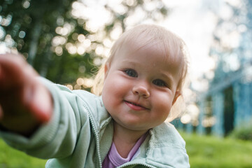 Cute blonde babe kid baby crawls right into the camera face in the park