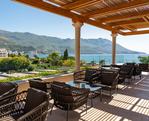 Wicker chairs and tables on the outdoor terrace of a coastal cafe