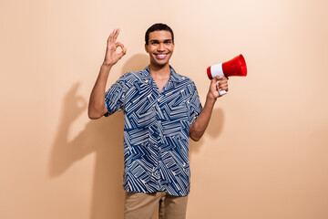 Photo portrait of handsome young guy show okey symbol hold megaphone dressed stylish blue print...